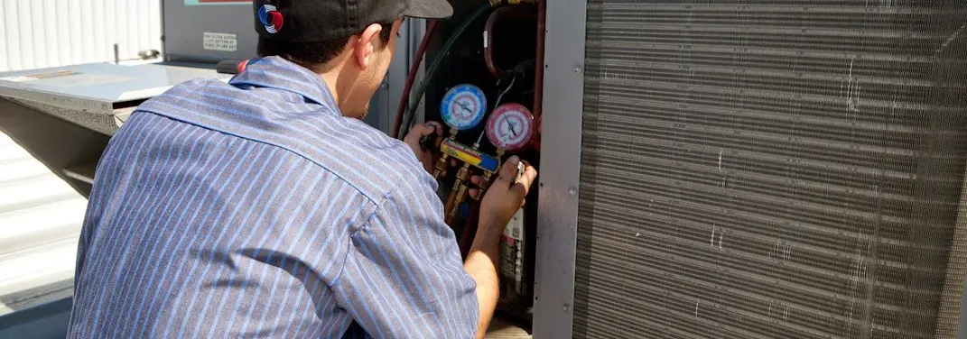 HVAC technician servicing a condenser unit in Freetown